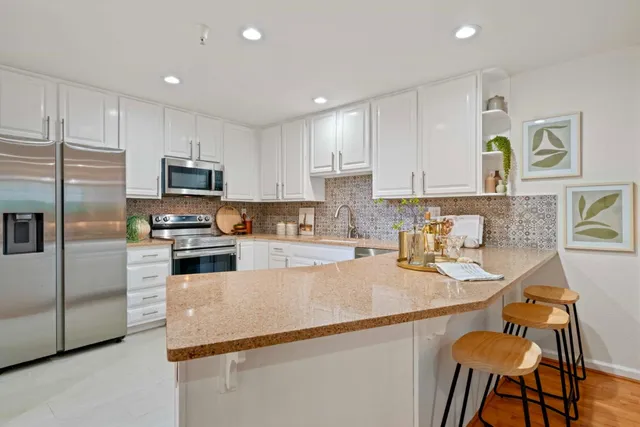 a kitchen with granite countertop a sink stainless steel appliances and white cabinets