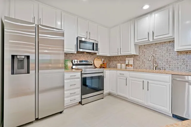 a kitchen with white cabinets stainless steel appliances and a sink
