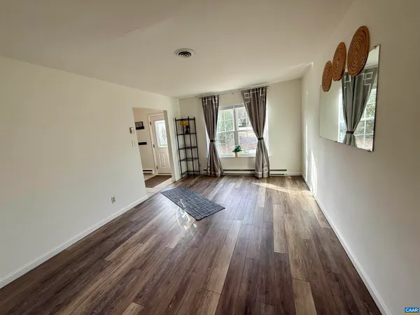 a view of a livingroom with wooden floor and furniture