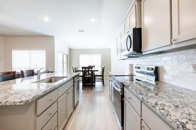 a kitchen with stainless steel appliances granite countertop a sink stove and cabinets