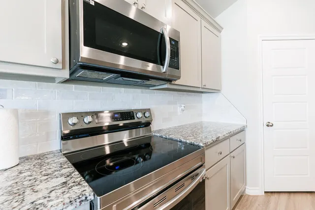 a kitchen with stainless steel appliances granite countertop a stove microwave and sink