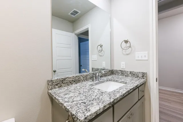 a bathroom with a granite countertop sink and a mirror