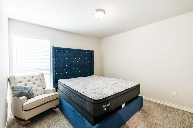 a bed sitting in a bedroom next to a window with cabinet