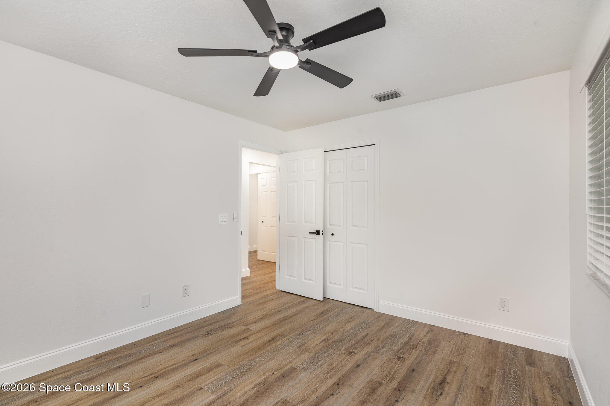362 Nikomas Way Melbourne Beach, FL 32951 - Photo 16 of 32 an empty room with wooden floor ceiling fan and windows