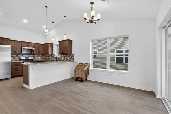 a kitchen with stainless steel appliances granite countertop a refrigerator a stove a microwave oven a sink with island and chairs with wooden floor