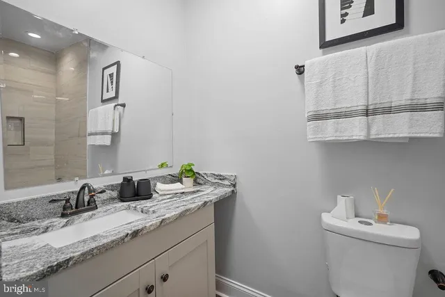 a bathroom with a granite countertop sink and a toilet