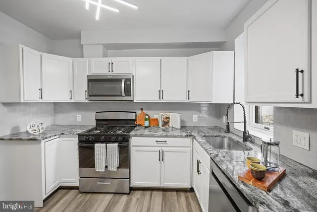 a kitchen with granite countertop a sink a stove and cabinets