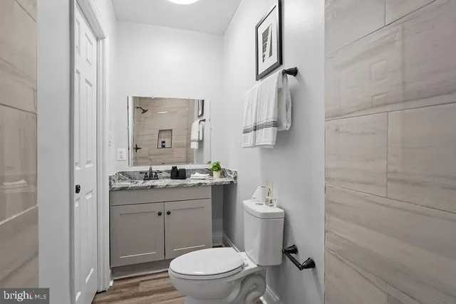 a bathroom with a granite countertop toilet a sink and a mirror