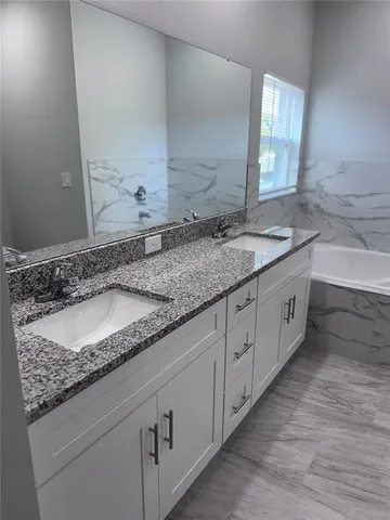 a bathroom with a granite countertop sink and a large mirror