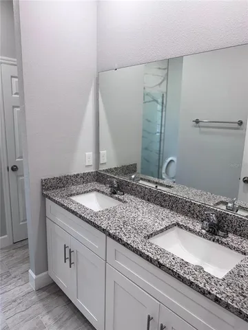 a bathroom with a granite countertop sink and a mirror