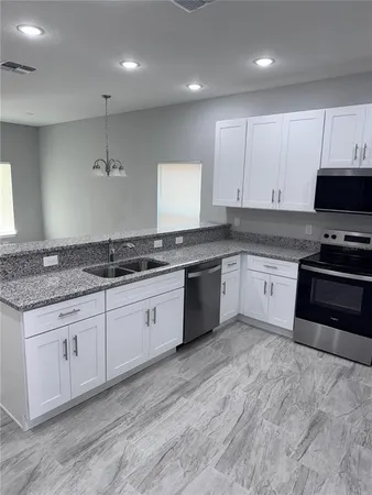 a large kitchen with stainless steel appliances granite countertop a stove a sink and a granite counter tops