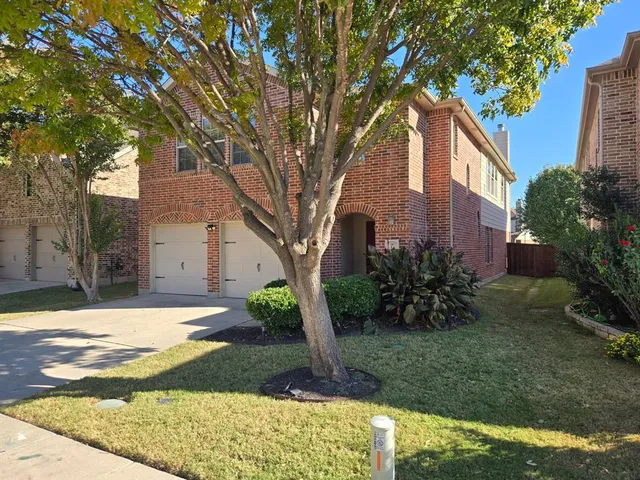 a tree in front of a brick house with a large tree