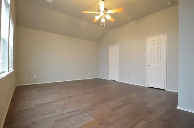an empty room with windows and chandelier fan