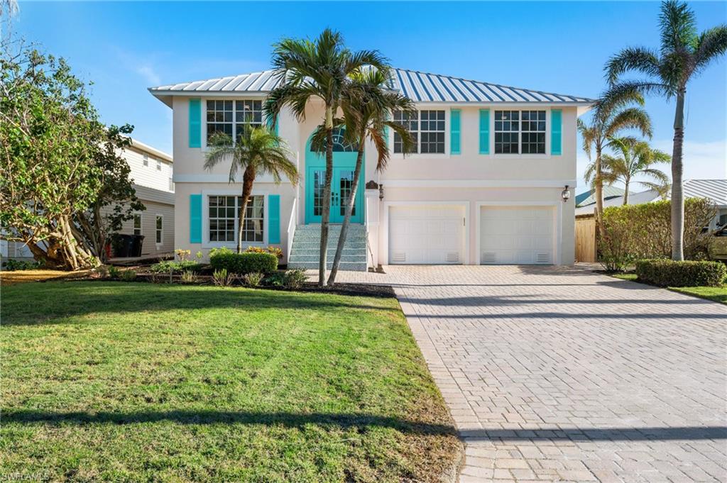 256 Curlew Street Fort Myers Beach, FL 33931 - Photo 1 of 43 View of front facade featuring a garage and a front lawn. virtually enhanced photo