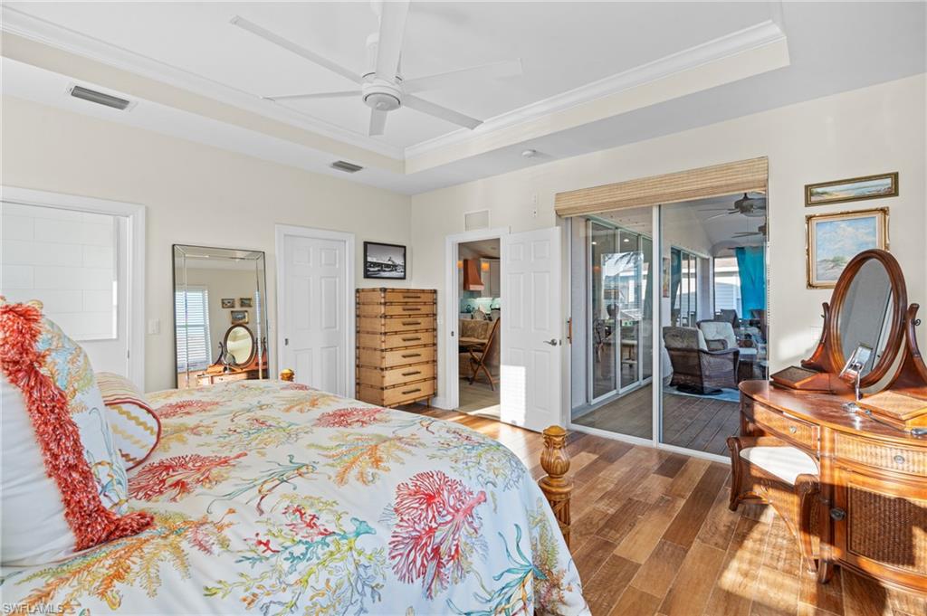 256 Curlew Street Fort Myers Beach, FL 33931 - Photo 19 of 43 Bedroom with a raised ceiling, hardwood / wood-style floors, access to exterior, and ceiling fan. virtually enhanced photo