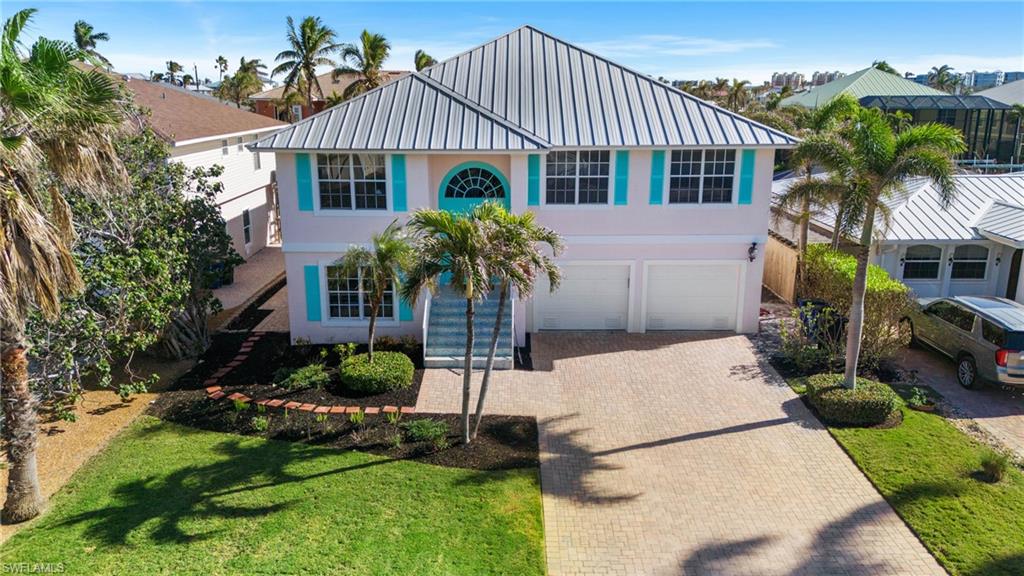 256 Curlew Street Fort Myers Beach, FL 33931 - Photo 2 of 43 View of front of property featuring a garage and a front lawn. virtually enhanced photo