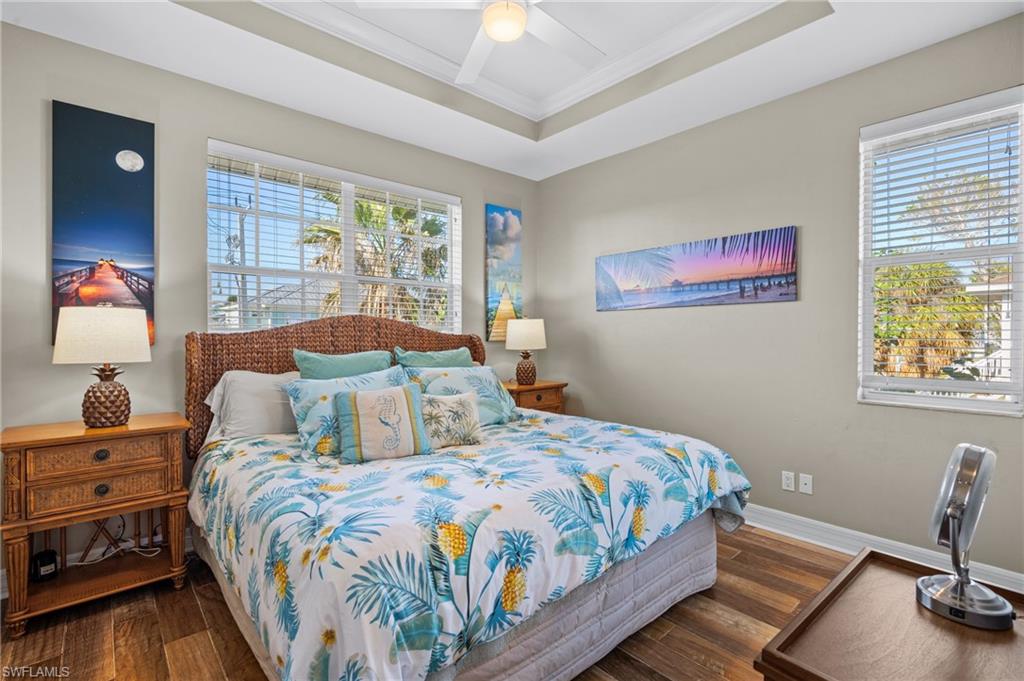 256 Curlew Street Fort Myers Beach, FL 33931 - Photo 26 of 43 Bedroom with ceiling fan, a raised ceiling, and multiple windows. virtually enhanced photo