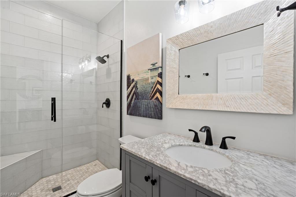 256 Curlew Street Fort Myers Beach, FL 33931 - Photo 28 of 43 Bathroom featuring vanity, an enclosed shower, and toilet. virtually enhanced photo