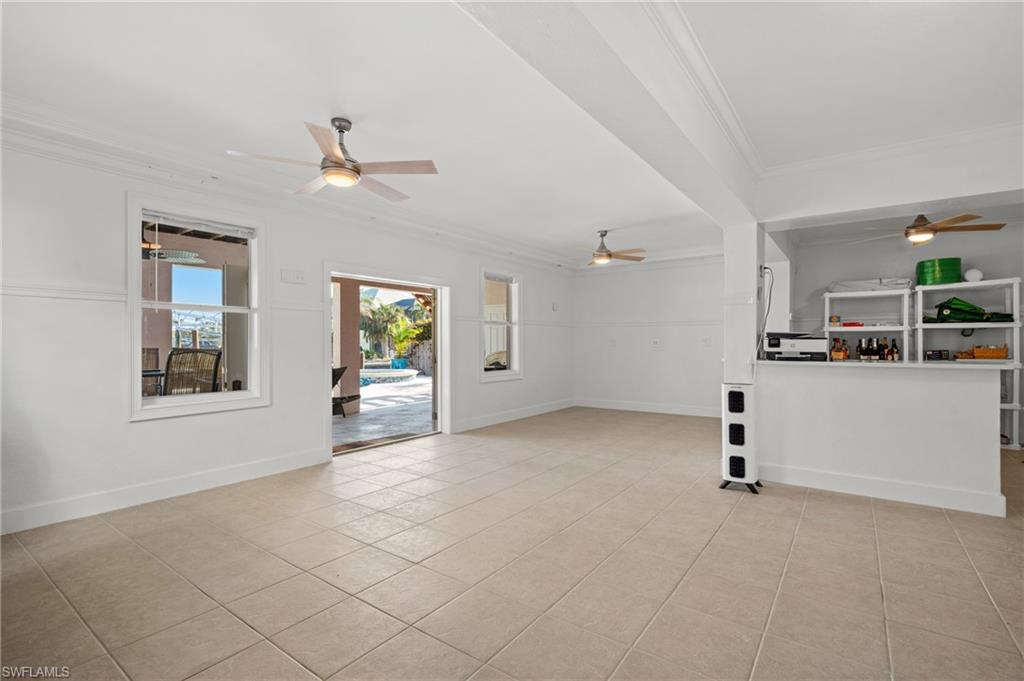 256 Curlew Street Fort Myers Beach, FL 33931 - Photo 31 of 43 Unfurnished living room with crown molding, ceiling fan, and light tile patterned floors. virtually enhanced photo