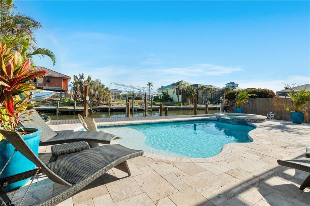 256 Curlew Street Fort Myers Beach, FL 33931 - Photo 32 of 43 View of pool featuring an in ground hot tub, a water view, and a patio. virtually enhanced photo