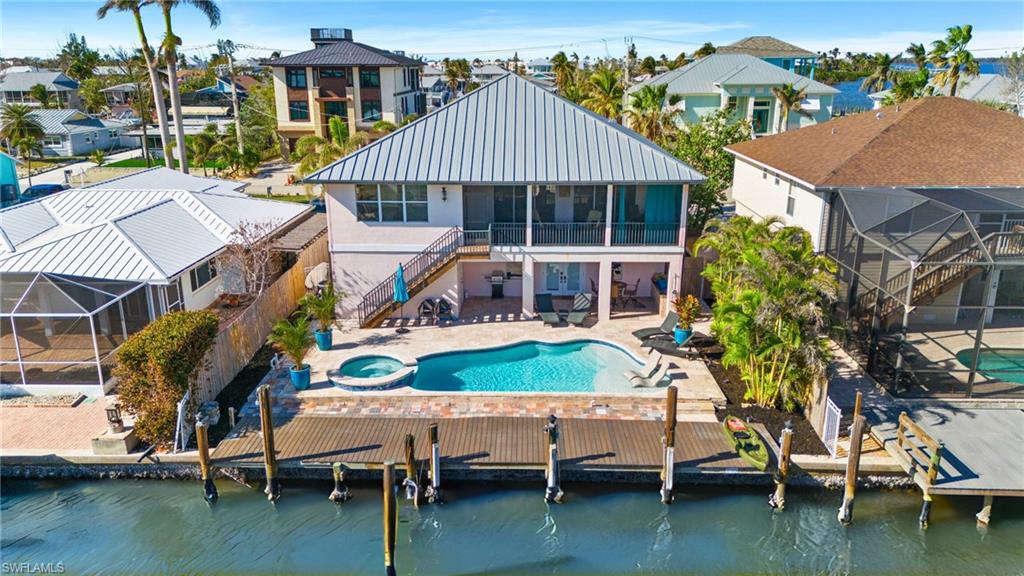 256 Curlew Street Fort Myers Beach, FL 33931 - Photo 34 of 43 VIRTUALLY ENHANCED - Rear view of property with a swimming pool with hot tub, a water view, a sunroom, and a patio area