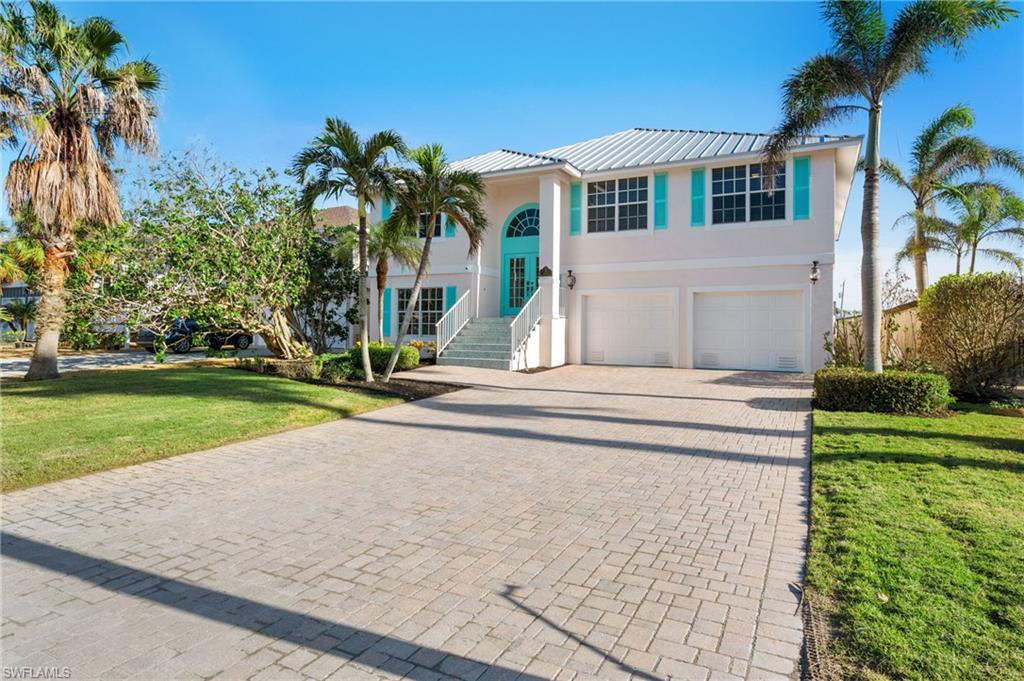 256 Curlew Street Fort Myers Beach, FL 33931 - Photo 40 of 43 View of front of house with a garage and a front yard. virtually enhanced photo