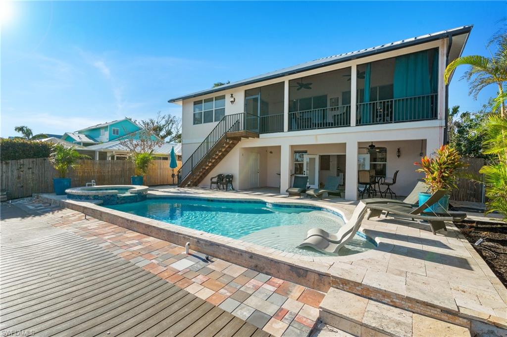 256 Curlew Street Fort Myers Beach, FL 33931 - Photo 4 of 43 View of swimming pool featuring an in ground hot tub, a sunroom, ceiling fan, and a patio area. virtually enhanced photo
