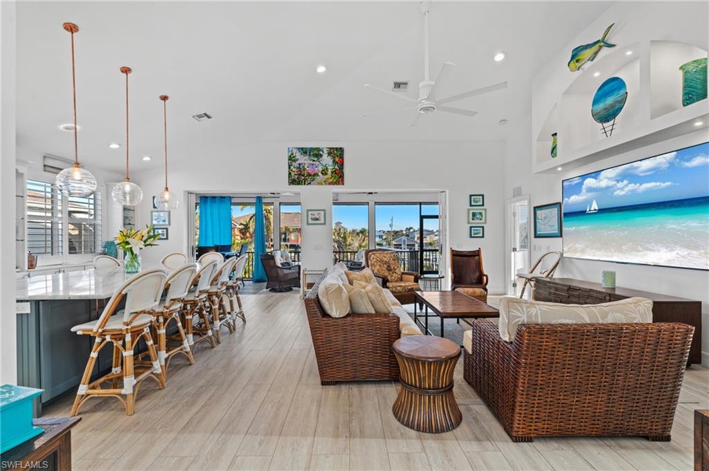 256 Curlew Street Fort Myers Beach, FL 33931 - Photo 8 of 43 Living room featuring high vaulted ceiling, ceiling fan, and light wood-type flooring. virtually enhanced photo