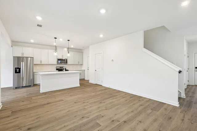 a kitchen with kitchen island white cabinets a sink dishwasher and a stove with wooden floor