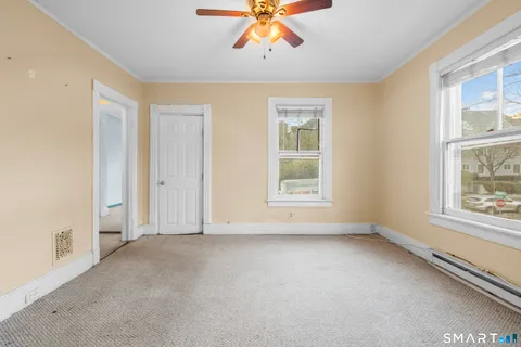 an empty room with chandelier fan and windows