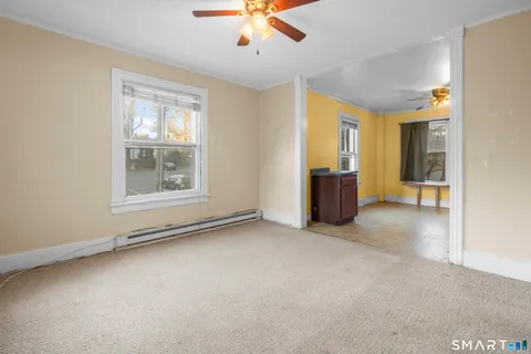 an empty room with chandelier fan and windows