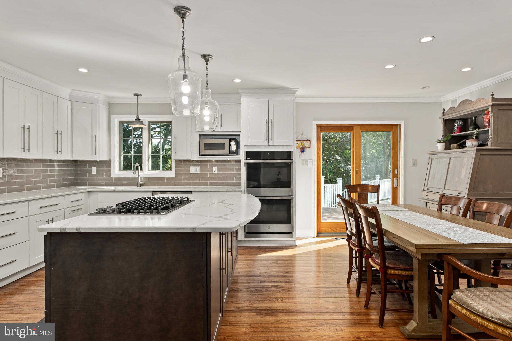 1429 Flat Rock Road Penn Valley, PA 19072 - Photo 20 of 58 a kitchen with stainless steel appliances granite countertop a stove a refrigerator a kitchen island a dining table and chairs with wooden floor