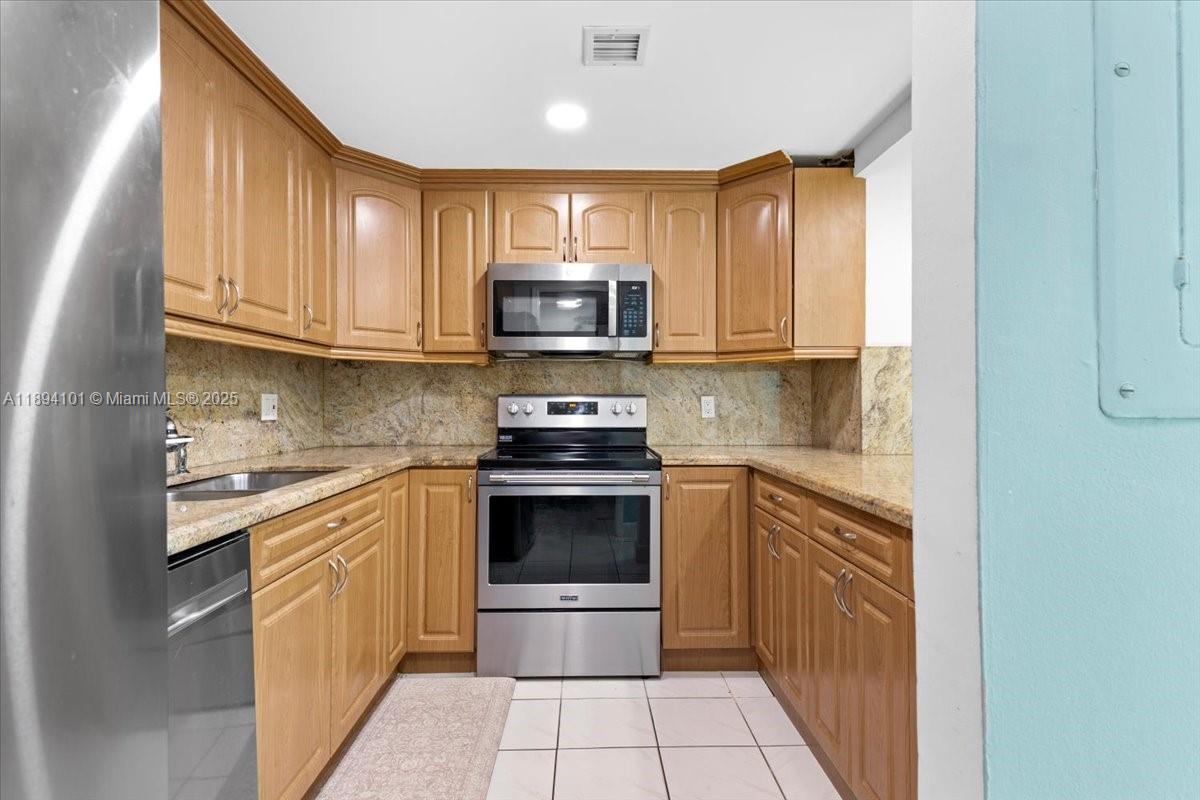 9450 Live Oak Place, Unit 109 Davie, FL 33324 - Photo 12 of 98 a kitchen with stainless steel appliances granite countertop a stove a sink and a microwave