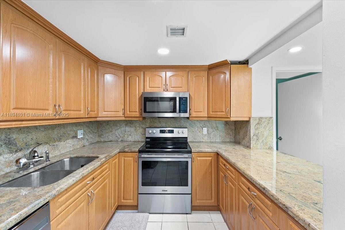 9450 Live Oak Place, Unit 109 Davie, FL 33324 - Photo 17 of 98 a kitchen with stainless steel appliances granite countertop a stove a sink and a microwave