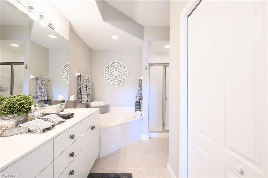 2371 Ravenna Boulevard, Unit 101 Naples, FL 34109 - Photo 15 of 44 Bathroom featuring vanity, separate shower and tub, and tile patterned flooring
