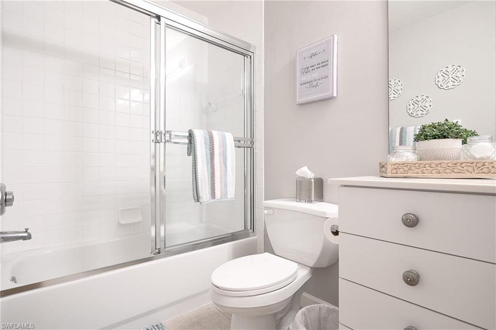 2371 Ravenna Boulevard, Unit 101 Naples, FL 34109 - Photo 19 of 44 Full bathroom featuring tile patterned flooring, bath / shower combo with glass door, vanity, and toilet