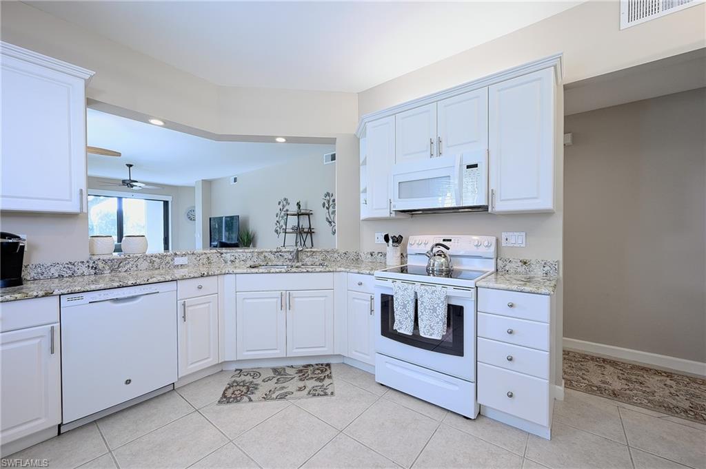2371 Ravenna Boulevard, Unit 101 Naples, FL 34109 - Photo 9 of 44 Kitchen featuring white cabinets, light tile patterned floors, and white appliances