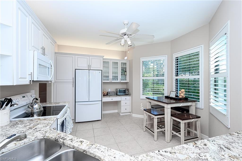 2371 Ravenna Boulevard, Unit 101 Naples, FL 34109 - Photo 10 of 44 Kitchen featuring ceiling fan, white cabinets, light stone counters, sink, and white appliances