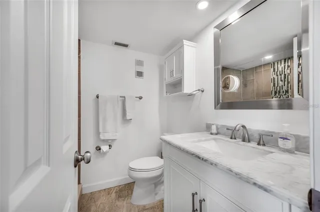 a bathroom with a granite countertop sink a toilet and a mirror