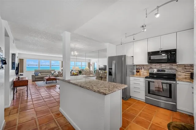 a kitchen with stainless steel appliances granite countertop a stove top oven a sink dishwasher a dining table and chairs