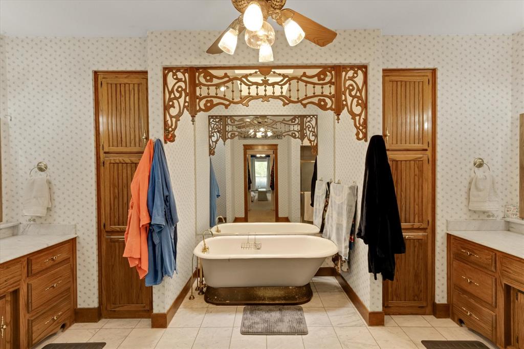 2717 Clear Lake Road Weatherford, TX 76087 - Photo 19 of 40 Freestanding bathtub centered between two wood-finish vanity cabinets with stone countertops, Sky light in primary bathroom