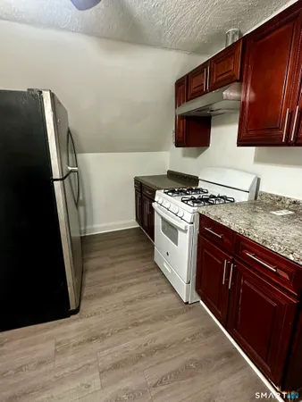 a kitchen with stainless steel appliances granite countertop a refrigerator a stove and a sink