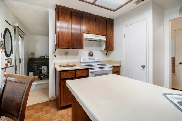 a kitchen with stainless steel appliances a sink a stove a refrigerator cabinets and chairs