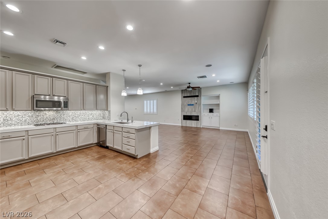2122 Mooreview Street Henderson, NV 89012 - Photo 7 of 44 A contemporary open-concept space features a well-appointed kitchen flowing into a living area with a sleek fireplace.