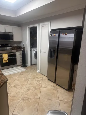 a kitchen with granite countertop a refrigerator and a stove top oven