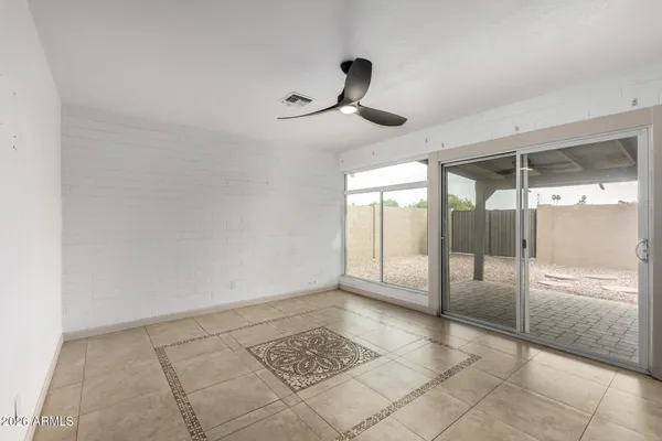 an empty room with a ceiling fan and window