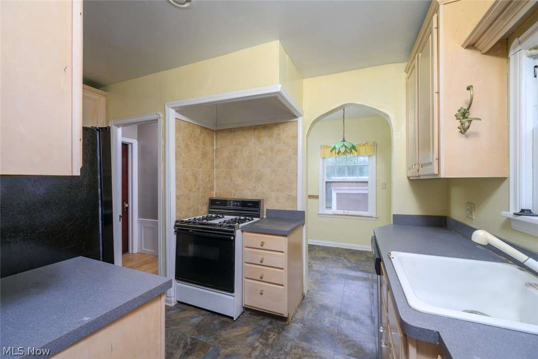 3869 Montevista Road Cleveland, OH 44121 - Photo 13 of 43 Kitchen with white gas range oven, black refrigerator, pendant lighting, sink, and dark tile flooring