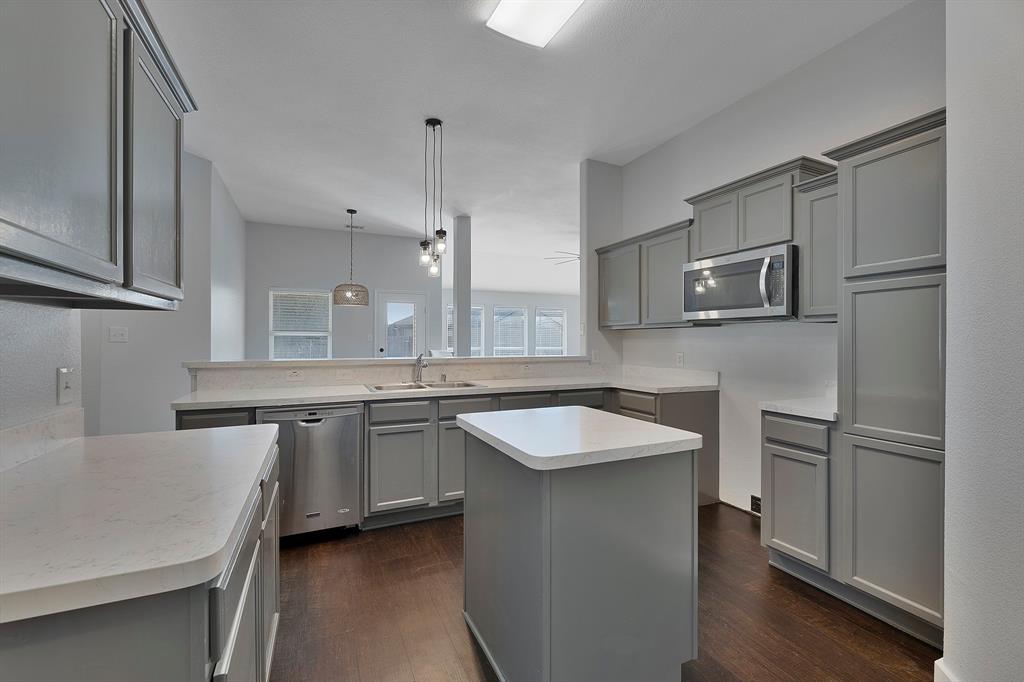 605 Clearbrook Street Azle, TX 76020 - Photo 6 of 33 Kitchen featuring gray shaker-style cabinetry, light-toned countertops, stainless steel appliances, a center island, and wood-finish flooring