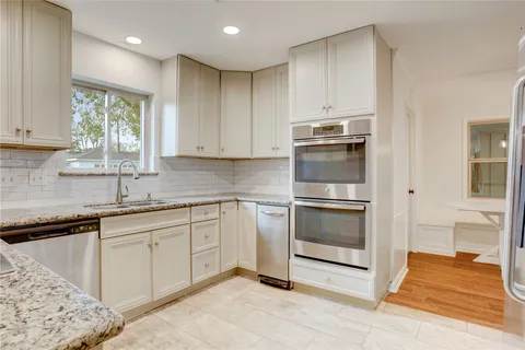a kitchen with granite countertop white cabinets and stainless steel appliances