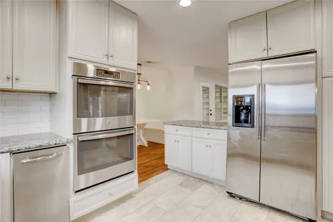 a kitchen with white cabinets and refrigerator